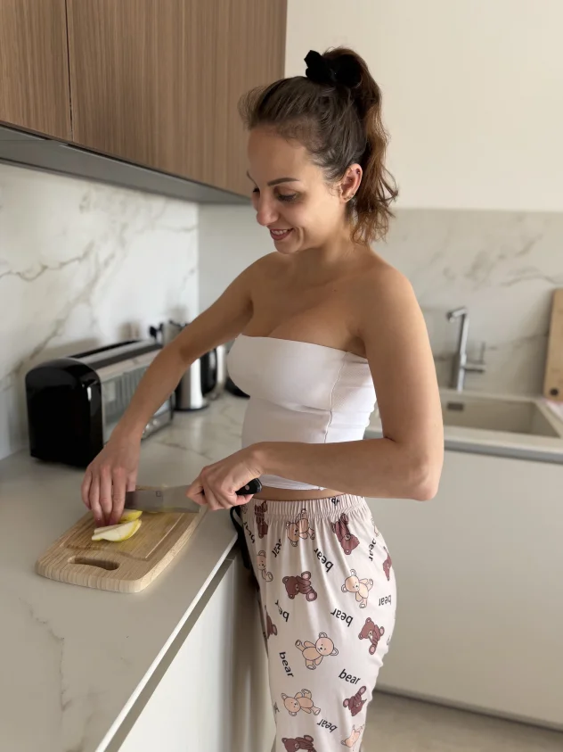 En la cocina, cortando una manzana… con un top blanco ajustado 